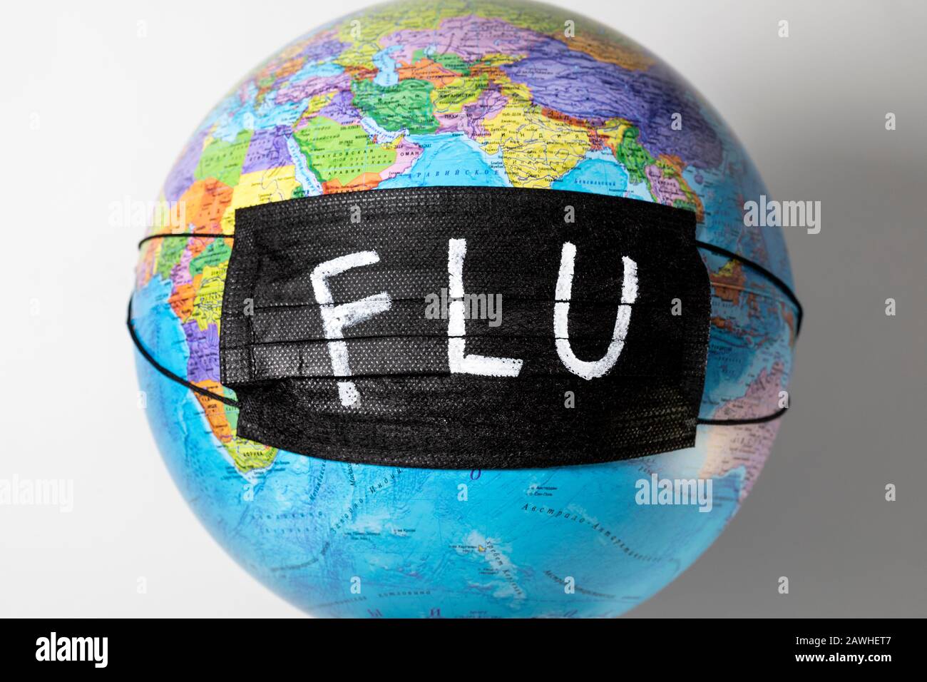 Globe with a political map of the world with a black medical mask and the inscription `FLU` Stock Photo